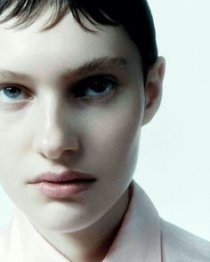 a close up of a person wearing a pink shirt and tie with short black hair