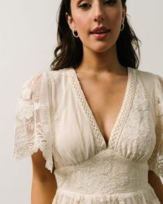 a woman wearing a white dress and earrings