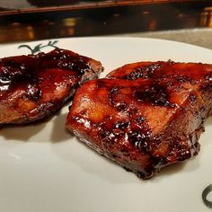 two pieces of meat sitting on top of a white plate