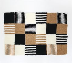 a black, white and brown patchwork rug on a white background with the pattern in squares