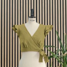 Wrap crop moss green top, short, sleeveless and with two ruffles on the shoulder, it has five pleats under the chest. It closes with a bow that goes around the waist and ties on the left side that we can adjust more or less. Ideal for events, it is a versatile top that we can combine in different looks and styles. Made of premium quality linen, it is a natural, fresh and breathable fabric. Green Non-stretch Summer Top, Summer Sleeveless Blouse Crop Top For Day Out, Sleeveless Blouse Crop Top For Summer Day Out, Chic Linen Crop Top For Spring, Sleeveless Summer Crop Top For Day Out, Summer Sleeveless Crop Top For A Day Out, Trendy Ruffled Short Sleeve Crop Top, Non-stretch V-neck Summer Crop Top, Trendy Short Sleeve Ruffled Crop Top