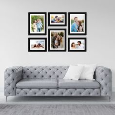 a gray couch sitting in front of a wall with pictures hanging on it's sides