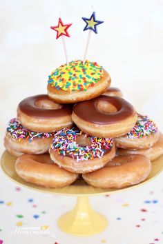 a pile of doughnuts with sprinkles and stars on top are sitting on a cake plate