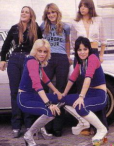 four women in matching outfits posing for a photo with their skateboards on the ground