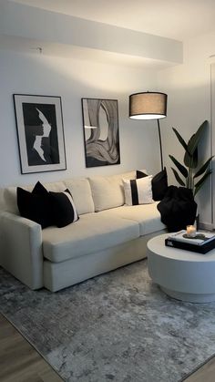 a modern living room with white furniture and art on the wall behind the couches