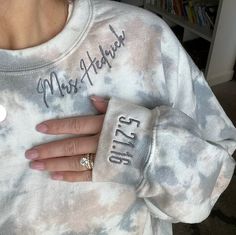 a woman wearing a tie dye sweatshirt with her hand on her chest and the words mrs hersfield written on it