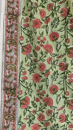 a green and pink floral print fabric with red flowers on the bottom half of it