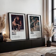 two framed movie posters on a wall above a bed in a room with large windows