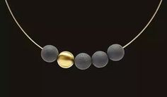 three stone necklaces are hanging from a gold plated chain on a black background