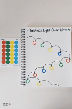 the christmas light color match book is next to a spiral notebook with colored circles on it