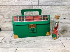 a green bag with a plaid design on it and a bottle next to the bag