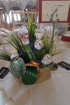 an arrangement of flowers in a basket on a table with place cards and wine glasses