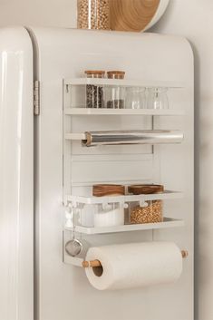 a white refrigerator freezer sitting inside of a kitchen next to a shelf filled with items