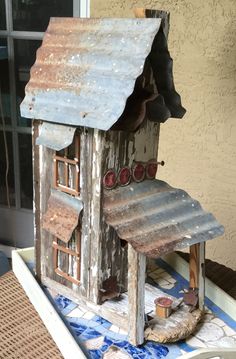 a birdhouse made out of old tin cans and some paint on the side of a house