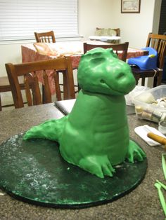 a green dinosaur cake sitting on top of a table