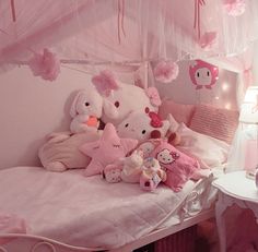 a pink bedroom with lots of stuffed animals on the bed