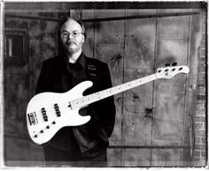 a man standing next to a white guitar