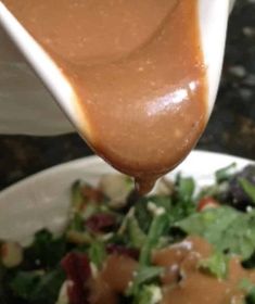 a spoon is pouring sauce on a salad