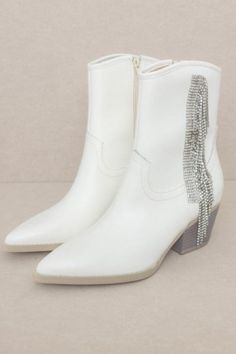 The rhinestone fringe cowboy boot made for a night out on the town. Elevate your style and energy to the next level with these dazzling rhinestone fringe cowboy boots. Perfect for a night out and sure to turn heads! SPECIFICATIONS: Shaft Height: 6.25" Heel Height: 2.25" The front platform: Types of closures: zipper Circumference of shoe opening: 10" Shaft circumference: 10" Y2K, WESTERN, SHORT, ANKLE, BOOTIE, BLING Made In: Imported Material Composition: Upper Material: Vegan Leather Insole Mate Western Rhinestone Fringe Boots For Fall, Western Boots With Rhinestone Fringe For Fall, Western Party Boots With Fringe, Western White Embellished Boots, White Rhinestone Boots For Spring, White Western Party Boots, White Rhinestone Boots For Fall, Glamorous White Boots With Rhinestones, Glamorous White Rhinestone Boots