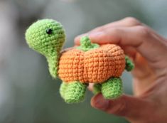 a small crocheted turtle is being held up by someone's hand,