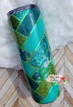 a blue and green tumbler cup sitting on top of a wooden floor next to white fur