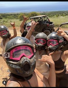 four girls wearing helmets and goggles are posing for the camera in front of an off - road vehicle