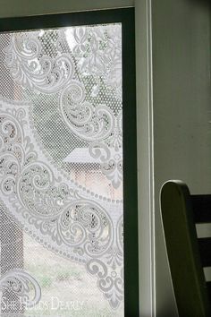 a chair sitting next to a window covered in white lace