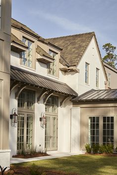 the front of a house with white walls and windows