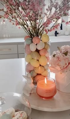 a vase filled with flowers and eggs on top of a table next to a candle