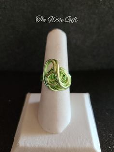 a green ring sitting on top of a white stand next to a black background with the words, the wise gift