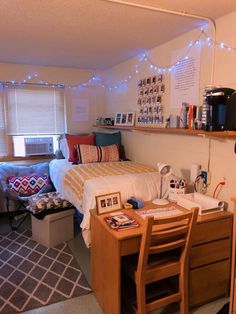 a dorm room with two beds and a desk in front of the bed is lit up by fairy lights