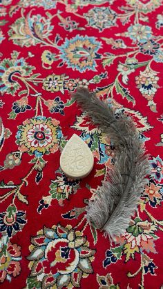 a feather laying on top of a red rug