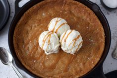 three ice cream balls sitting in a cast iron skillet with caramel drizzle