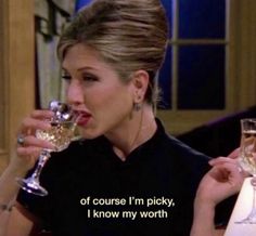 a woman drinking from a wine glass while sitting at a table