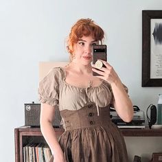 a woman taking a selfie with her cell phone in front of a bookcase