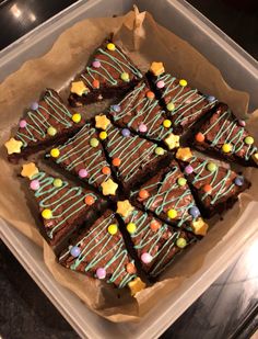 a tray filled with brownies covered in frosting and sprinkles on top of a table