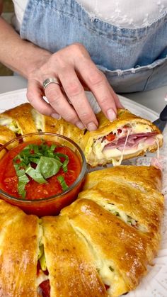 a person holding a plate with some food on it and dipping sauce in the middle