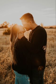 a man and woman kissing in an open field with the sun shining down on them