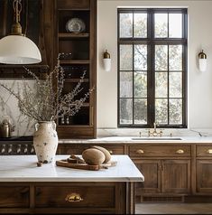 a kitchen with marble counter tops and wooden cabinets, along with a vase filled with flowers