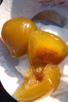 two pieces of fruit sitting on top of a white plate next to a fork and spoon