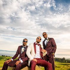 two men in suits are sitting on a rock