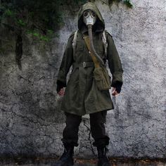 a man wearing a gas mask standing in front of a wall