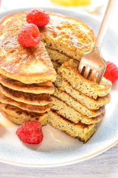 a stack of pancakes with raspberries on top and a fork in the middle