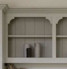 a white shelf with candles and books on it