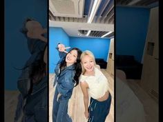 two women are posing for the camera in front of blue walls and wood flooring