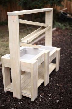 a wooden bench made out of pallets with a sink in the middle and two stools on each side