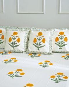 a bed with yellow flowers on it and green trim around the pillow cases, along with two matching throw pillows