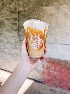 a hand holding up a starbucks drink with caramel swirl