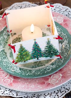 a lit candle is sitting in a box on a plate with other plates and napkins