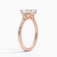 a rose gold engagement ring with an oval cut diamond in the center and side stones